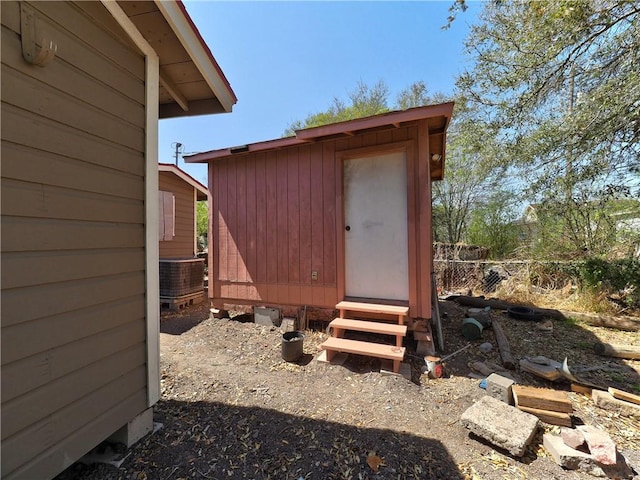 view of shed with central air condition unit and fence