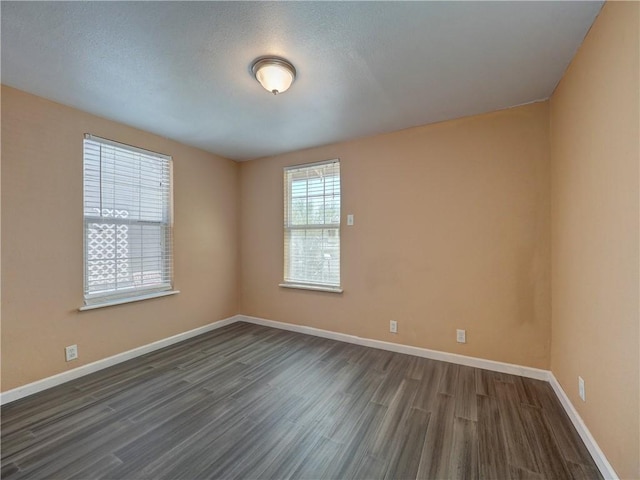 empty room with baseboards and dark wood-style flooring