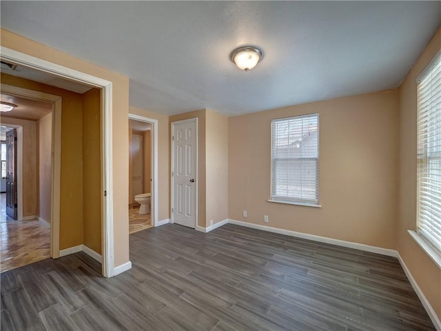 empty room with baseboards and dark wood-style flooring