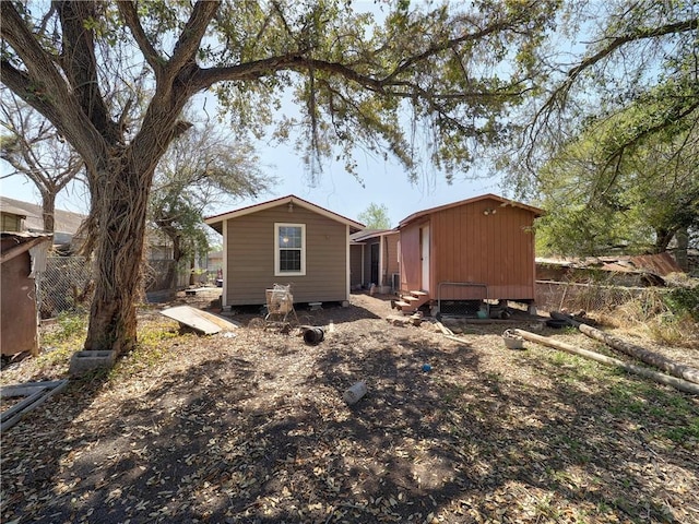 back of house with an outbuilding, fence, and entry steps