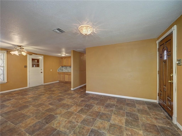 unfurnished living room with visible vents, baseboards, a ceiling fan, and stone finish flooring