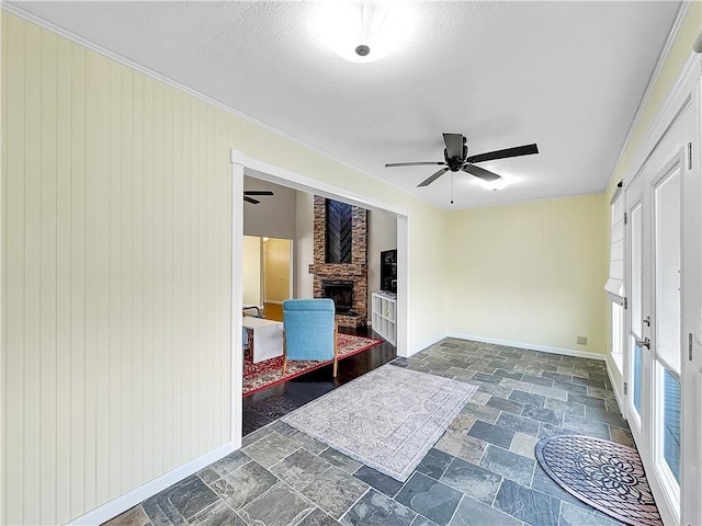 interior space featuring ceiling fan, wood walls, and a stone fireplace