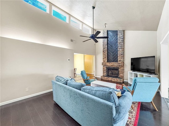 living room featuring ceiling fan, a stone fireplace, dark wood-type flooring, and high vaulted ceiling