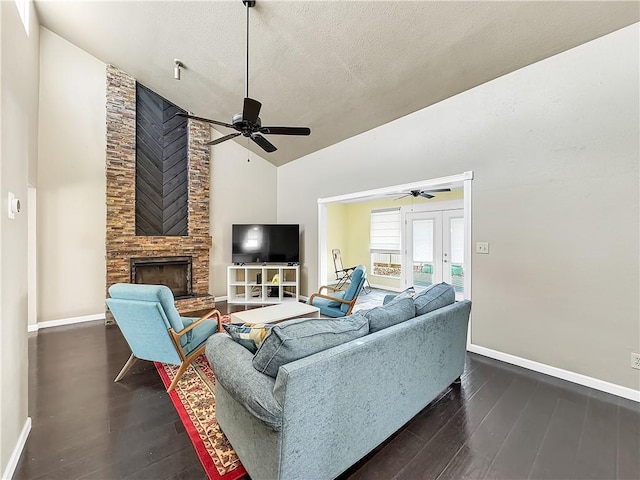 living room featuring ceiling fan, dark wood-type flooring, a fireplace, french doors, and a textured ceiling