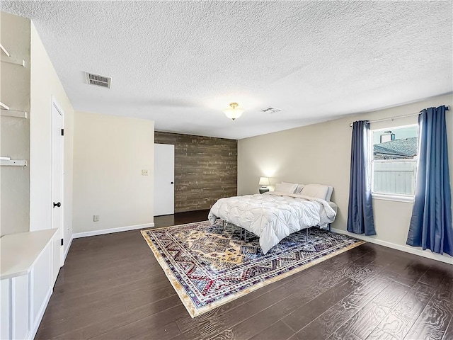 bedroom with a textured ceiling, dark hardwood / wood-style flooring, and wooden walls