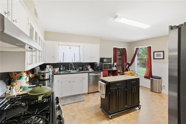 kitchen featuring light parquet floors, sink, black appliances, white cabinets, and a center island