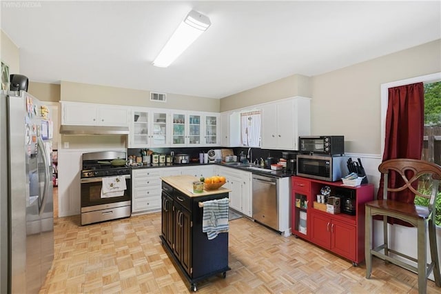 kitchen with white cabinets, sink, tasteful backsplash, a kitchen island, and stainless steel appliances