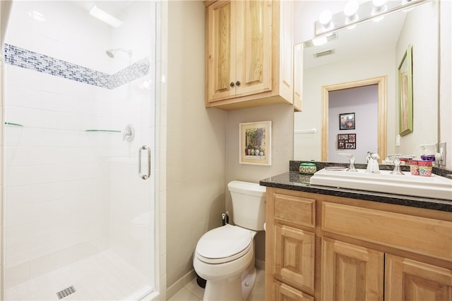 bathroom featuring a shower with shower door, vanity, toilet, and tile patterned flooring