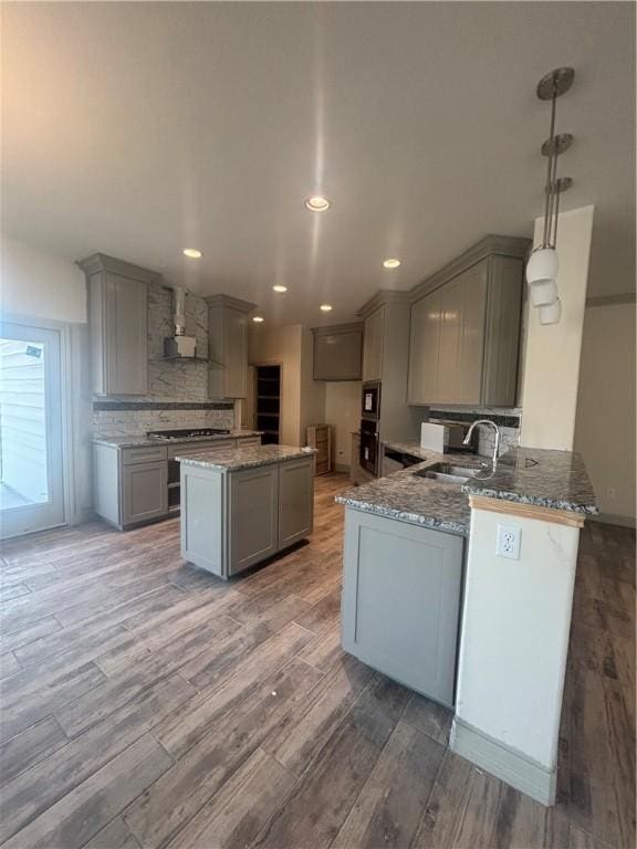 3101 Adak Ct, Corpus Christi, TX 78414 - kitchen featuring gray cabinetry, wall chimney exhaust hood, a sink, light stone counters, and light wood finished floors