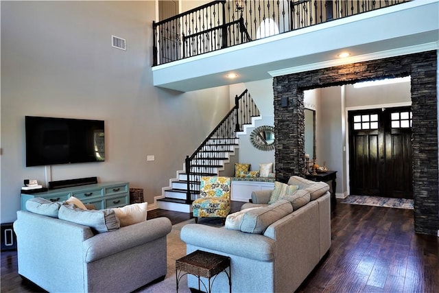 living room featuring visible vents, baseboards, stairs, hardwood / wood-style floors, and a high ceiling