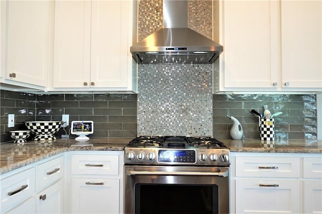 kitchen with stainless steel gas range oven, decorative backsplash, white cabinetry, and wall chimney exhaust hood