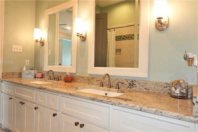 bathroom with double vanity, tiled shower, and a sink