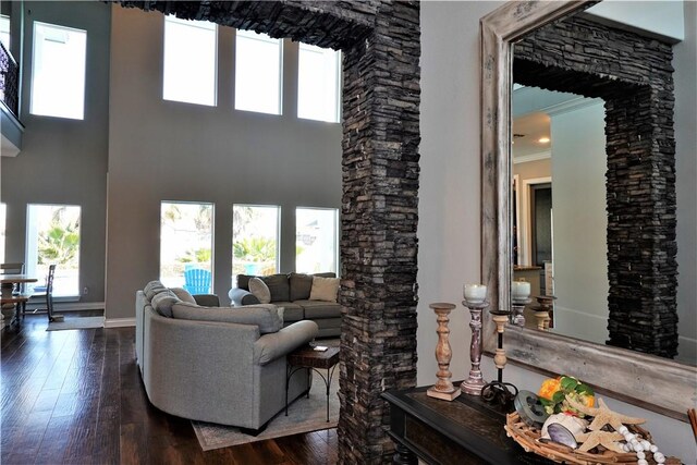 living room with dark wood-type flooring, crown molding, baseboards, and a towering ceiling