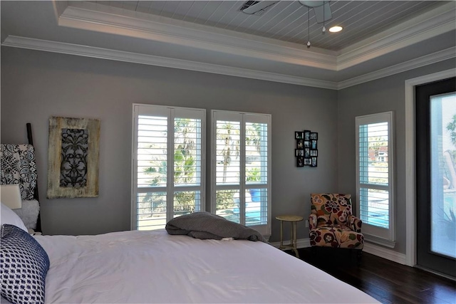 bedroom with wood finished floors, a raised ceiling, and ornamental molding