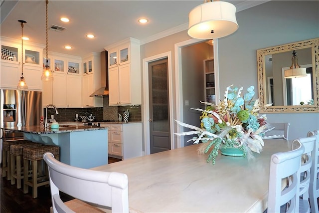 kitchen featuring a sink, glass insert cabinets, crown molding, wall chimney range hood, and backsplash