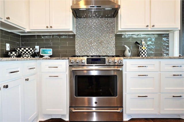 kitchen featuring decorative backsplash, gas range, wall chimney exhaust hood, and white cabinetry