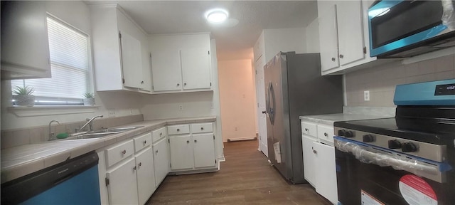 167 Shady Oak, Rockport, TX 78382 - kitchen featuring stainless steel appliances, tile countertops, white cabinetry, wood finished floors, and decorative backsplash