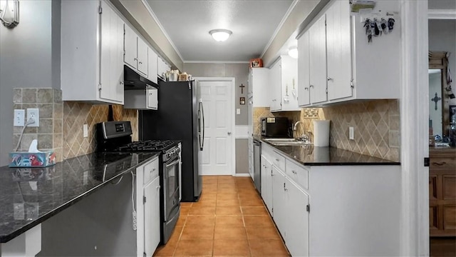 5301 Bromley Dr, Corpus Christi, TX 78413 - kitchen with appliances with stainless steel finishes, dark countertops, crown molding, light tile patterned floors, and white cabinetry