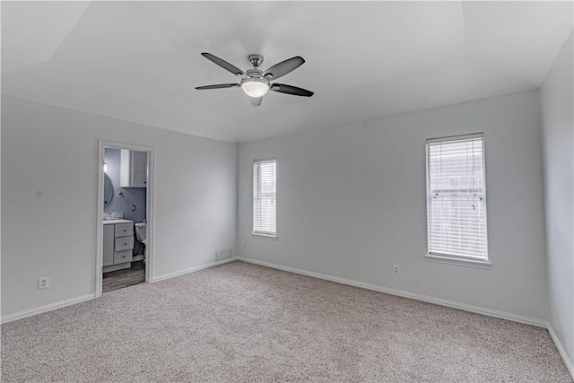 unfurnished bedroom featuring carpet floors, ceiling fan, ensuite bath, and baseboards