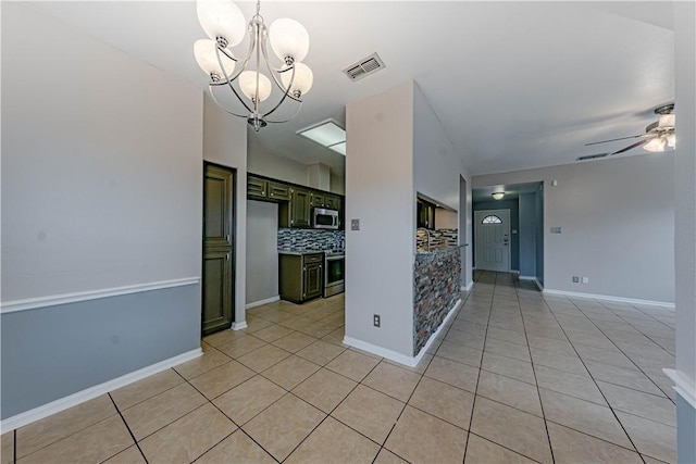 spare room featuring ceiling fan with notable chandelier, light tile patterned flooring, visible vents, and baseboards