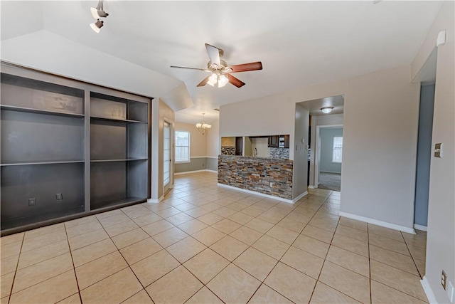 unfurnished room featuring light tile patterned floors, vaulted ceiling, ceiling fan with notable chandelier, and baseboards