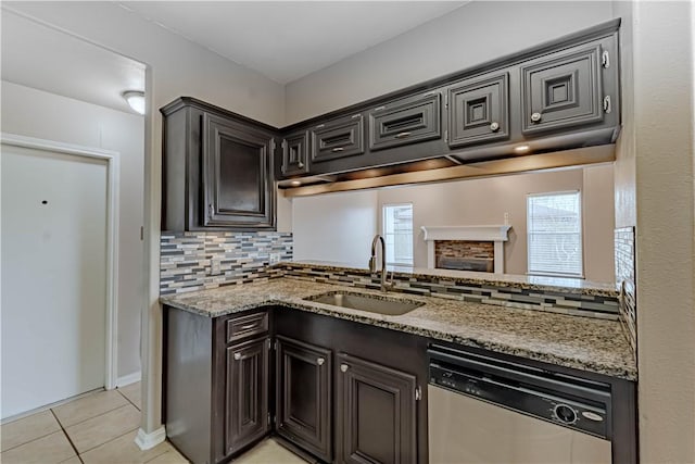 kitchen featuring light tile patterned floors, a sink, decorative backsplash, light stone countertops, and dishwasher