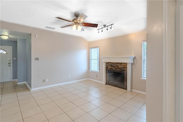 unfurnished living room featuring baseboards, visible vents, a ceiling fan, a fireplace, and light tile patterned flooring