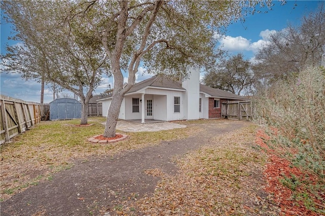 rear view of property with an outbuilding, a patio, a fenced backyard, a storage shed, and a chimney