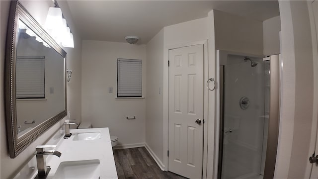 bathroom featuring hardwood / wood-style floors, vanity, a shower with shower door, and toilet