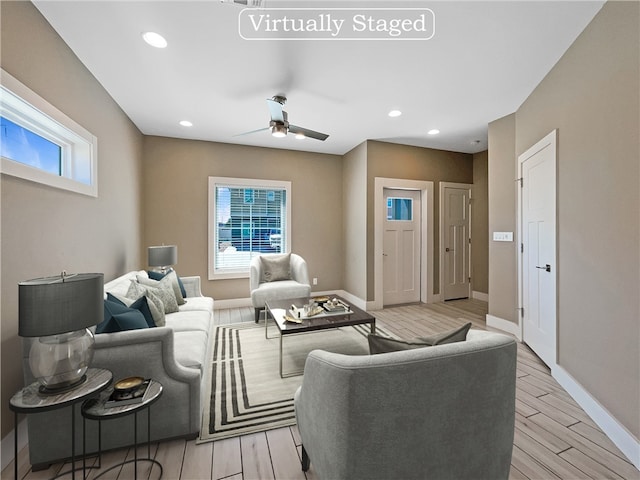 living room featuring light hardwood / wood-style floors, ceiling fan, and plenty of natural light