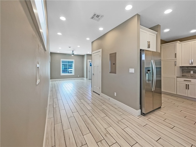 kitchen featuring white cabinetry, ceiling fan, light hardwood / wood-style flooring, electric panel, and stainless steel fridge