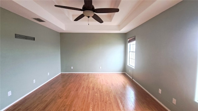 2906 Alice Ln, Kingsville, TX 78363 - empty room featuring a tray ceiling, baseboards, visible vents, a ceiling fan, and wood finished floors