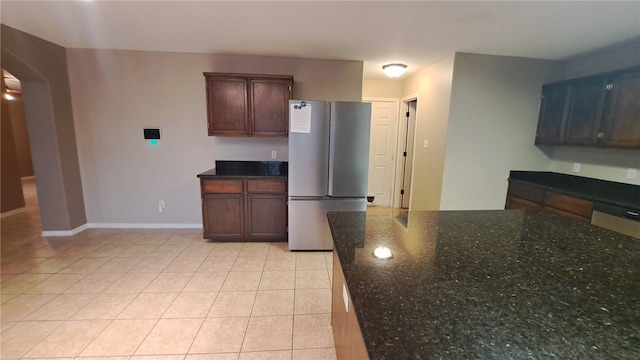 2906 Alice Ln, Kingsville, TX 78363 - kitchen featuring baseboards, freestanding refrigerator, dark stone countertops, and light tile patterned flooring