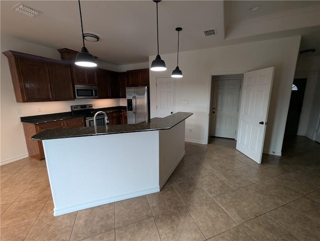 2905 Dante Dr, Corpus Christi, TX 78415 - kitchen featuring appliances with stainless steel finishes, light tile patterned floors, a kitchen island with sink, decorative light fixtures, and dark brown cabinetry