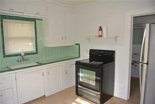 kitchen with electric range, tile counters, white refrigerator, decorative backsplash, and white cabinets