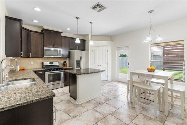 8129 Resplandor St, Corpus Christi, TX 78414 - kitchen featuring appliances with stainless steel finishes, a sink, dark brown cabinets, tasteful backsplash, and a kitchen island