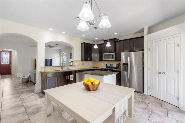 8129 Resplandor St, Corpus Christi, TX 78414 - kitchen with stainless steel appliances, a sink, arched walkways, dark brown cabinets, and decorative backsplash