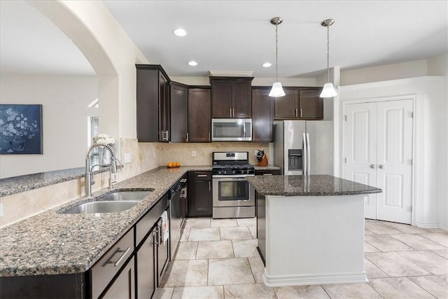 8129 Resplandor St, Corpus Christi, TX 78414 - kitchen featuring stainless steel appliances, a sink, dark brown cabinetry, dark stone counters, and arched walkways
