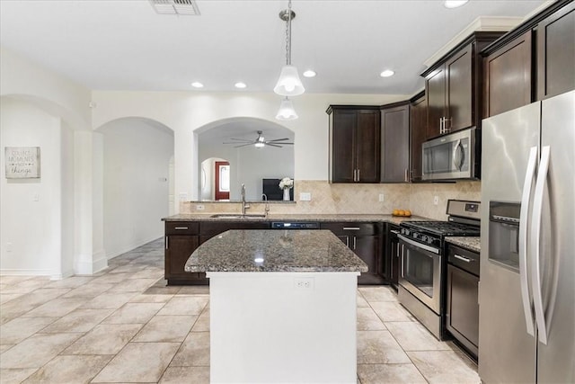 8129 Resplandor St, Corpus Christi, TX 78414 - kitchen with appliances with stainless steel finishes, arched walkways, ceiling fan, dark stone countertops, and tasteful backsplash