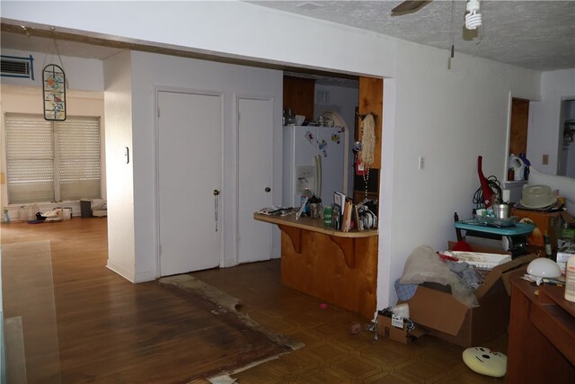 interior space featuring white fridge with ice dispenser and a textured ceiling