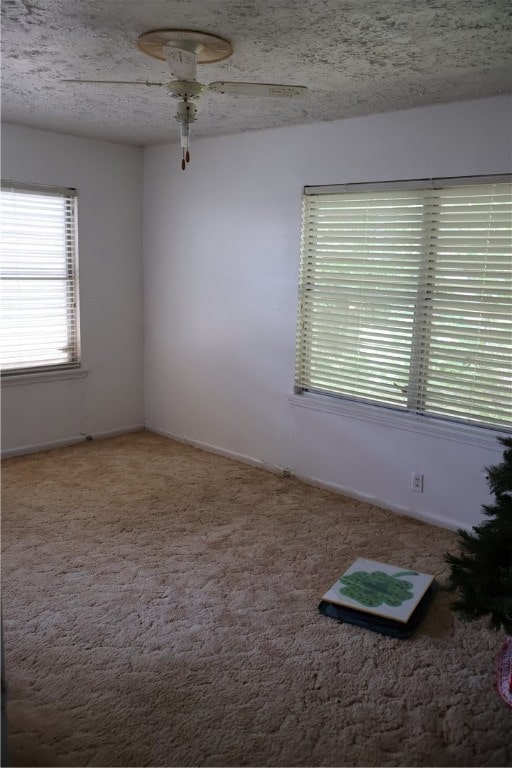 carpeted spare room with a textured ceiling and ceiling fan