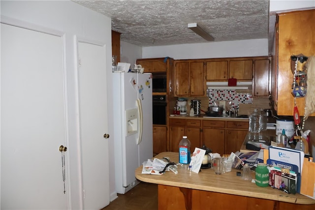 kitchen featuring black oven, backsplash, a textured ceiling, white fridge with ice dispenser, and kitchen peninsula