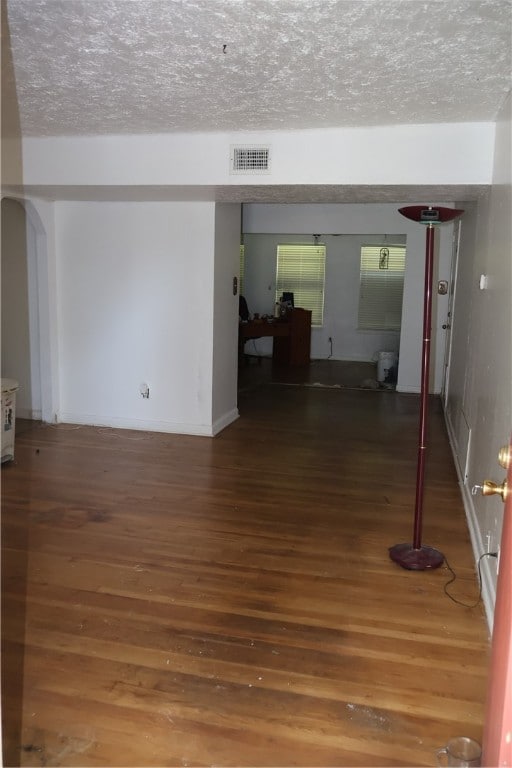 empty room with a textured ceiling and dark hardwood / wood-style floors