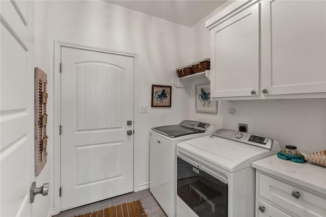 laundry area featuring cabinets, separate washer and dryer, and light hardwood / wood-style floors