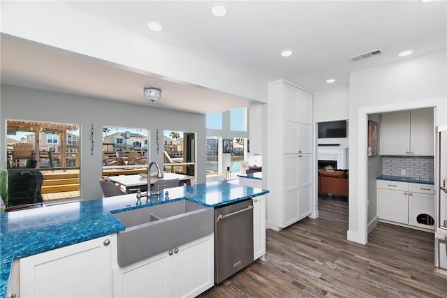 kitchen with dark wood-type flooring, a sink, recessed lighting, a fireplace, and dishwasher