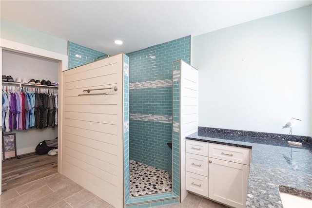 full bath with recessed lighting, tiled shower, a spacious closet, and wood tiled floor