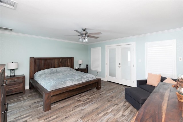 bedroom with crown molding, wood finished floors, visible vents, and french doors