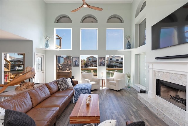 living room with wood finished floors, a high ceiling, ceiling fan, and a fireplace