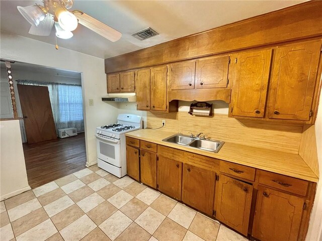 kitchen featuring white range with gas stovetop, ceiling fan, sink, and decorative backsplash