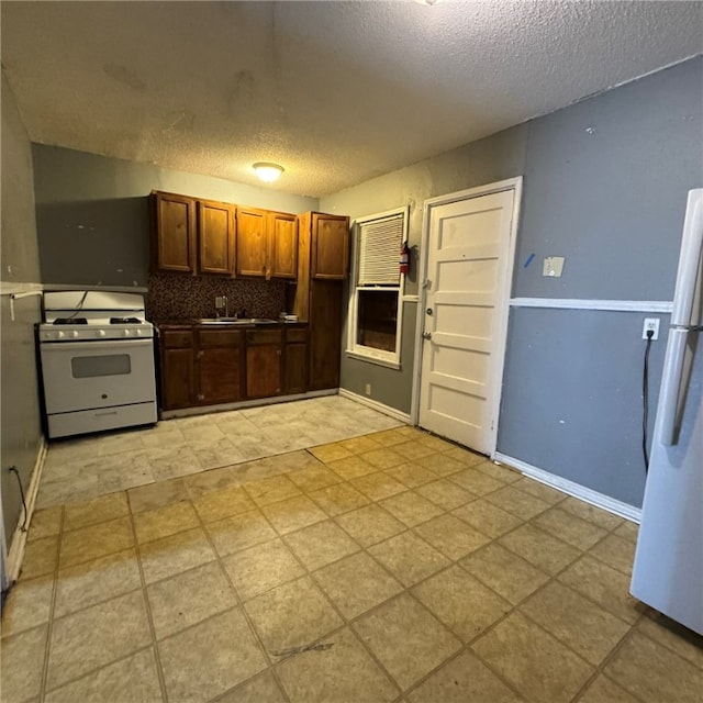 kitchen featuring sink, white appliances, a textured ceiling, and tasteful backsplash